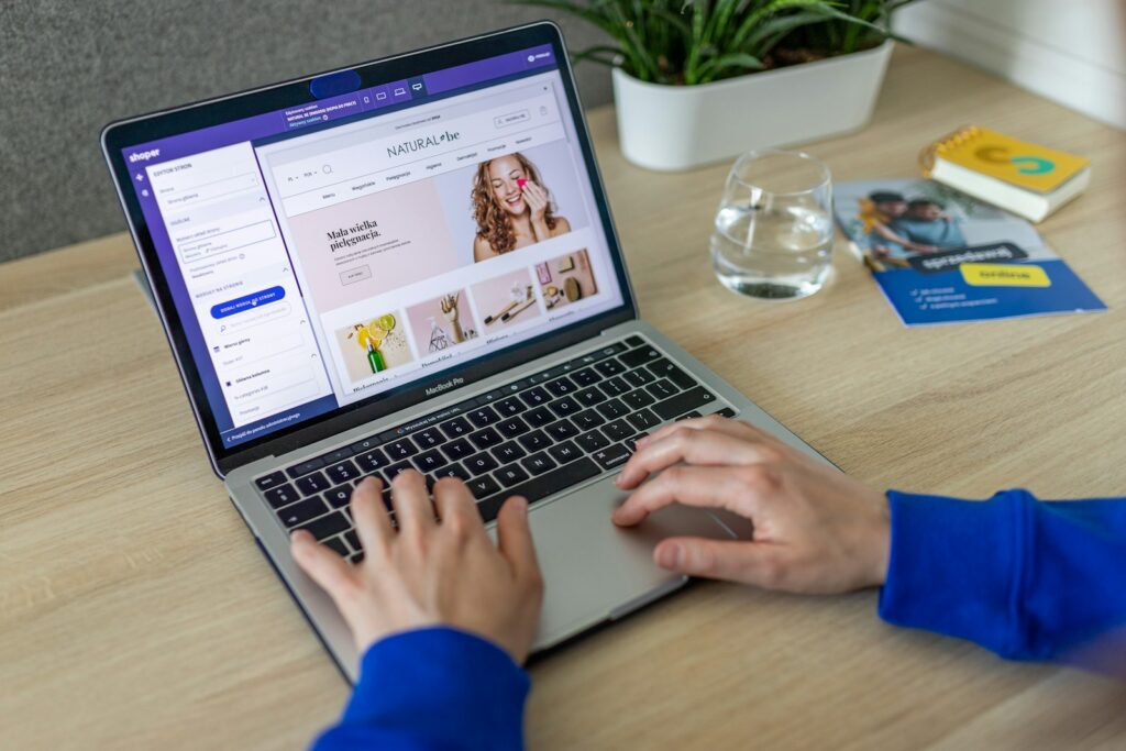 a person typing on a laptop on a table. Shopify and woocommerce